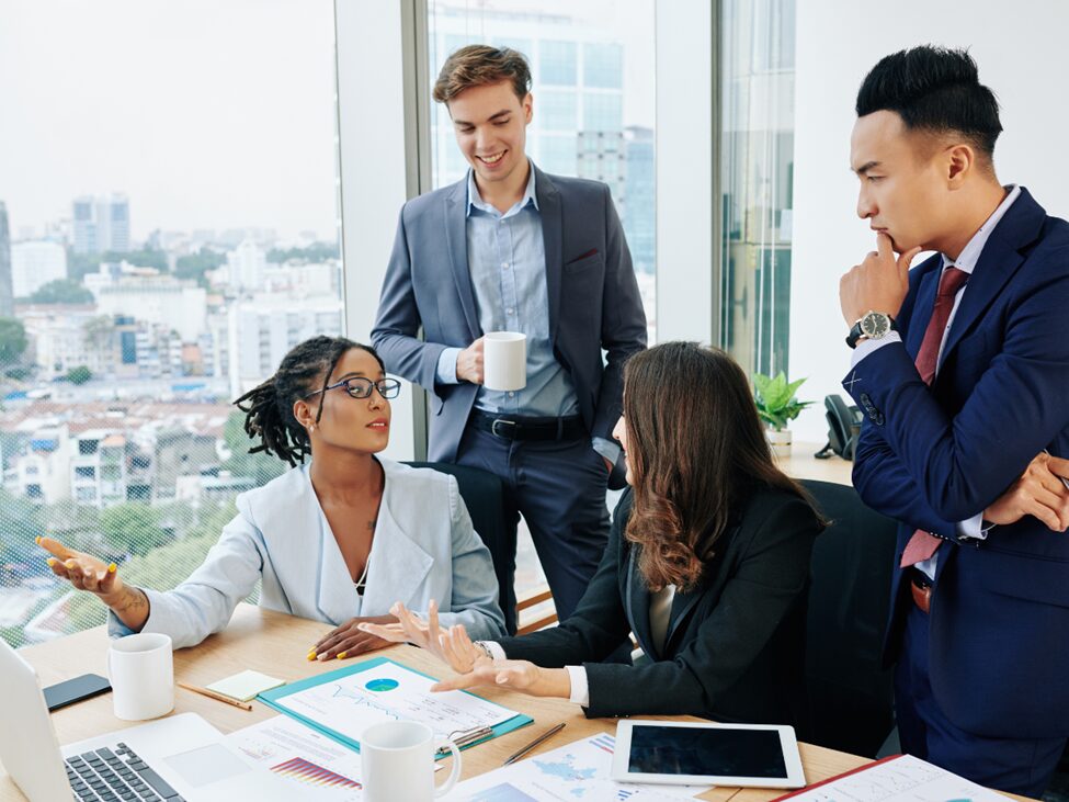 Four people talking and looking at papers on a desk